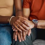 couple sitting together holding hands and smiling after years of marriage