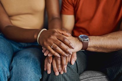 couple sitting together holding hands and smiling after years of marriage