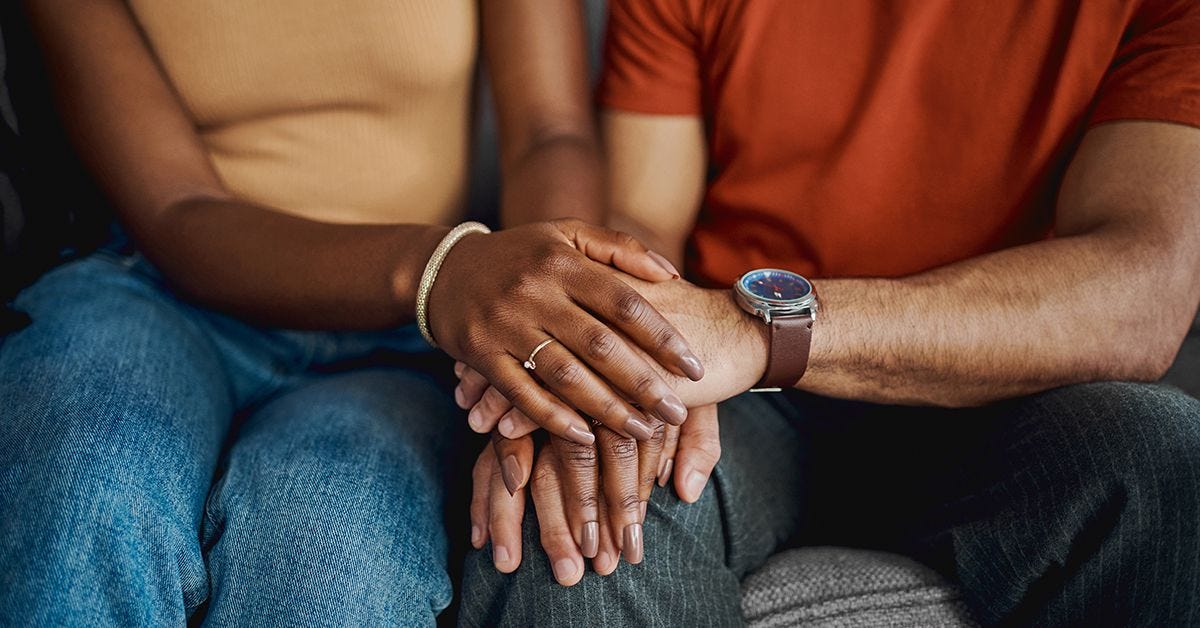 couple sitting together holding hands and smiling after years of marriage