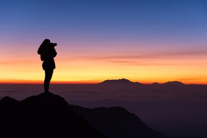 woman standing on a mountain peak looking at the sunrise, symbolizing life purpose