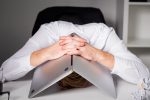 person surrounded by unfinished tasks, looking overwhelmed