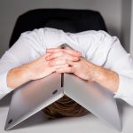 person surrounded by unfinished tasks, looking overwhelmed