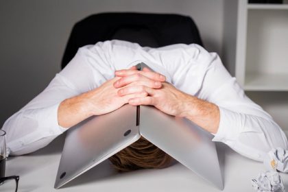 person surrounded by unfinished tasks, looking overwhelmed