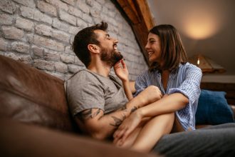 couple sitting apart on a couch looking frustrated, illustrating relationship strain