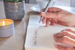 A person writing in a beautiful gratitude journal with a cup of coffee, representing the practice of gratitude and mindfulness