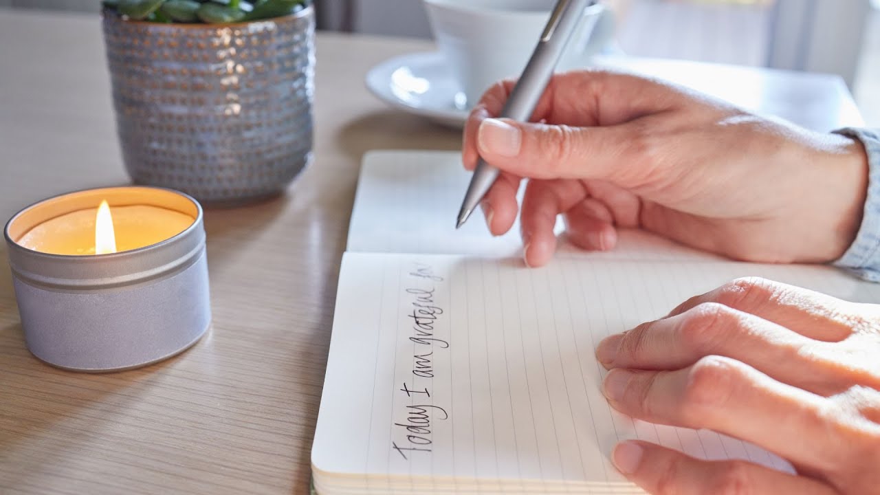 A person writing in a beautiful gratitude journal with a cup of coffee, representing the practice of gratitude and mindfulness