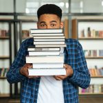 stack of inspiring books with a person reading thoughtfully